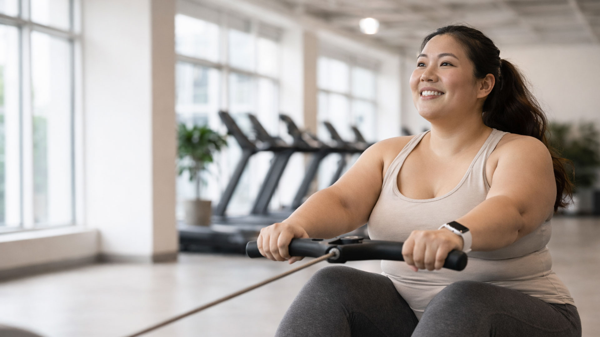 Smiling woman exercising on a rowing machine in a gym